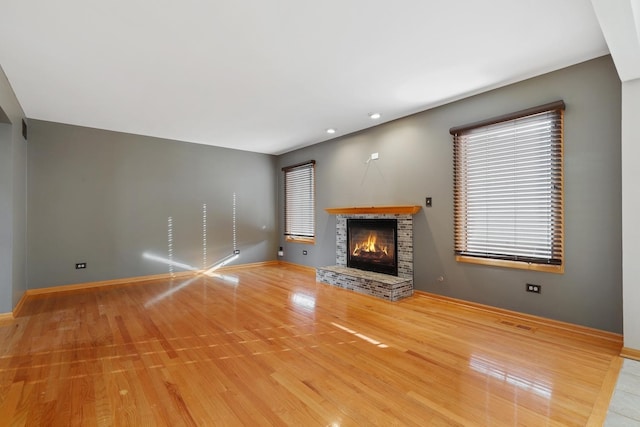 unfurnished living room featuring visible vents, wood finished floors, recessed lighting, baseboards, and a brick fireplace