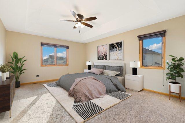 carpeted bedroom with a raised ceiling, baseboards, and ceiling fan