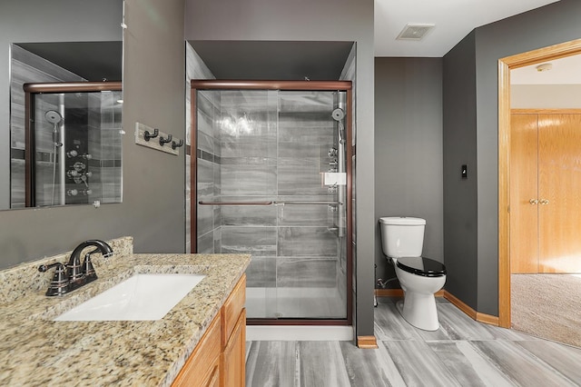 bathroom with vanity, baseboards, visible vents, a shower stall, and toilet