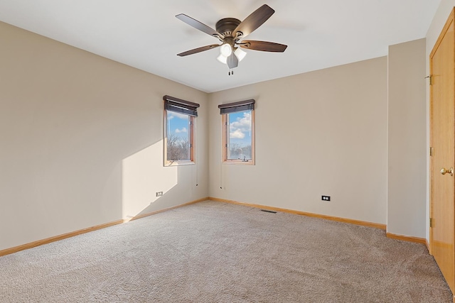 empty room with light carpet, visible vents, baseboards, and ceiling fan