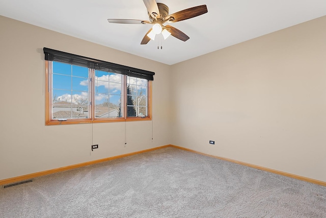 carpeted empty room with visible vents, baseboards, and a ceiling fan