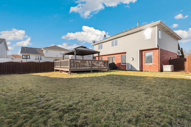 back of property with central AC unit, fence, a wooden deck, a yard, and brick siding