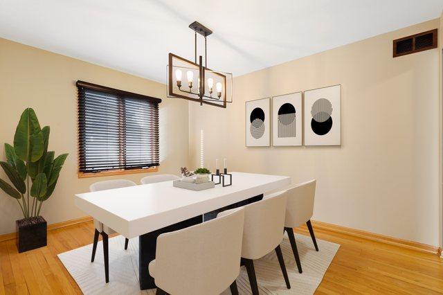 dining area featuring a notable chandelier, baseboards, visible vents, and light wood finished floors