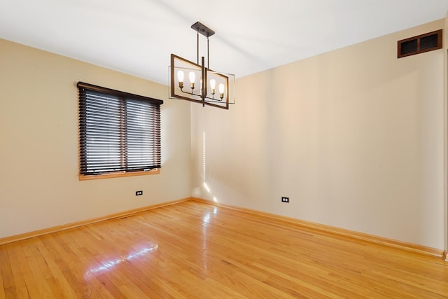 unfurnished room with a notable chandelier, visible vents, baseboards, and light wood-style floors