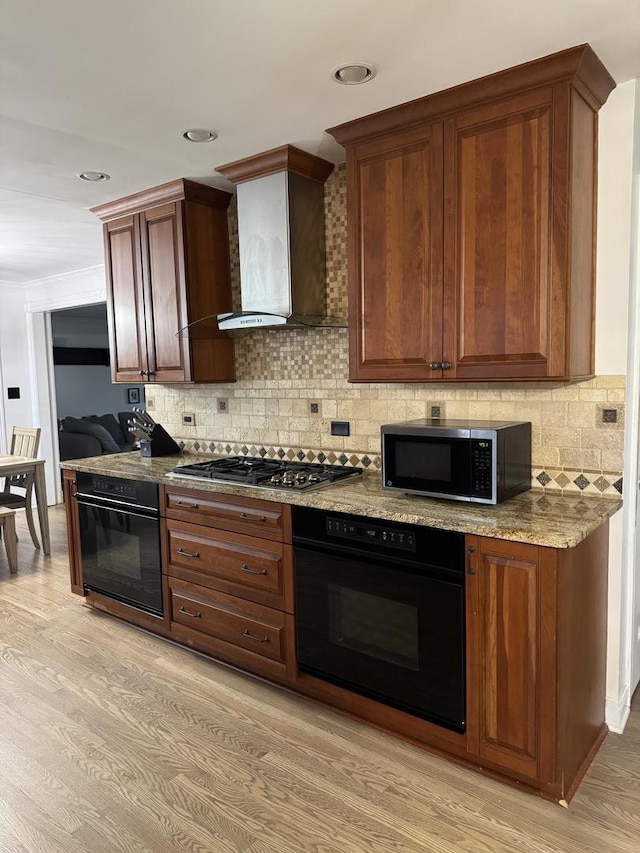 kitchen featuring light wood-style floors, tasteful backsplash, appliances with stainless steel finishes, and wall chimney exhaust hood