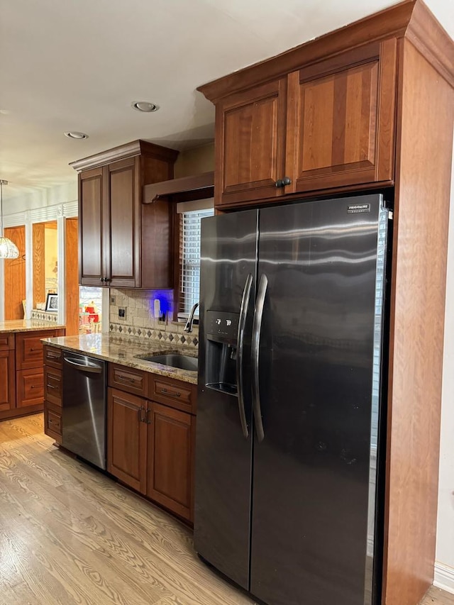 kitchen featuring stainless steel dishwasher, black fridge with ice dispenser, light wood finished floors, and a sink