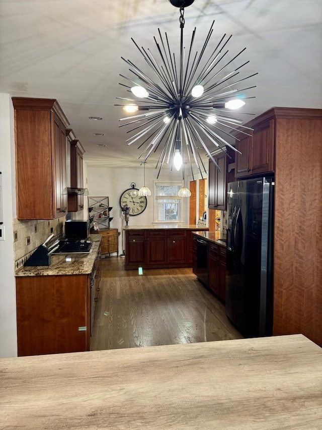 kitchen with a peninsula, dark wood-style flooring, black appliances, decorative light fixtures, and tasteful backsplash