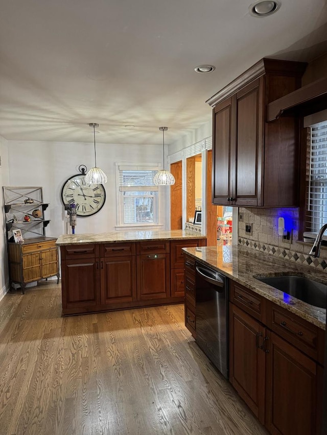 kitchen with light wood finished floors, a sink, backsplash, and stainless steel dishwasher