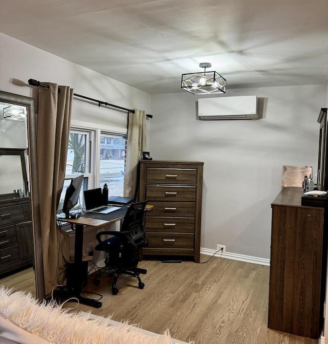 office featuring baseboards, light wood-style flooring, and a wall unit AC