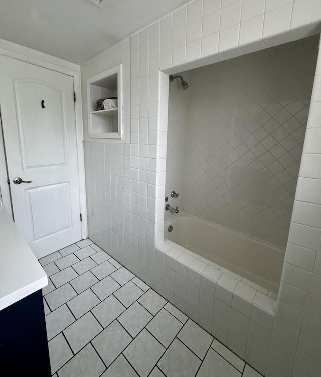 full bath featuring tile patterned floors, tiled shower / bath combo, tile walls, and vanity