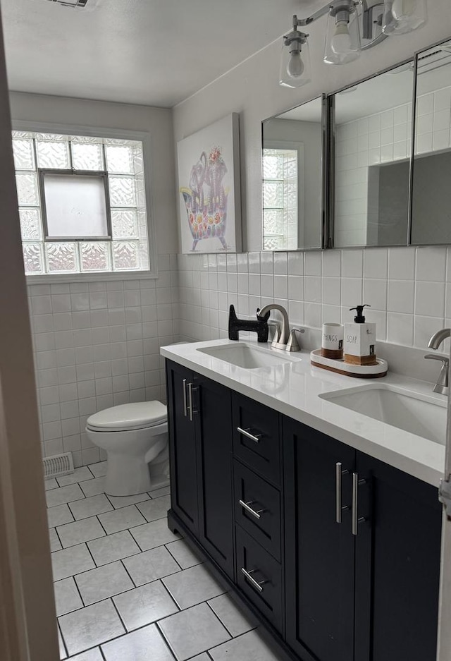 bathroom with a sink, toilet, tile walls, and tile patterned flooring