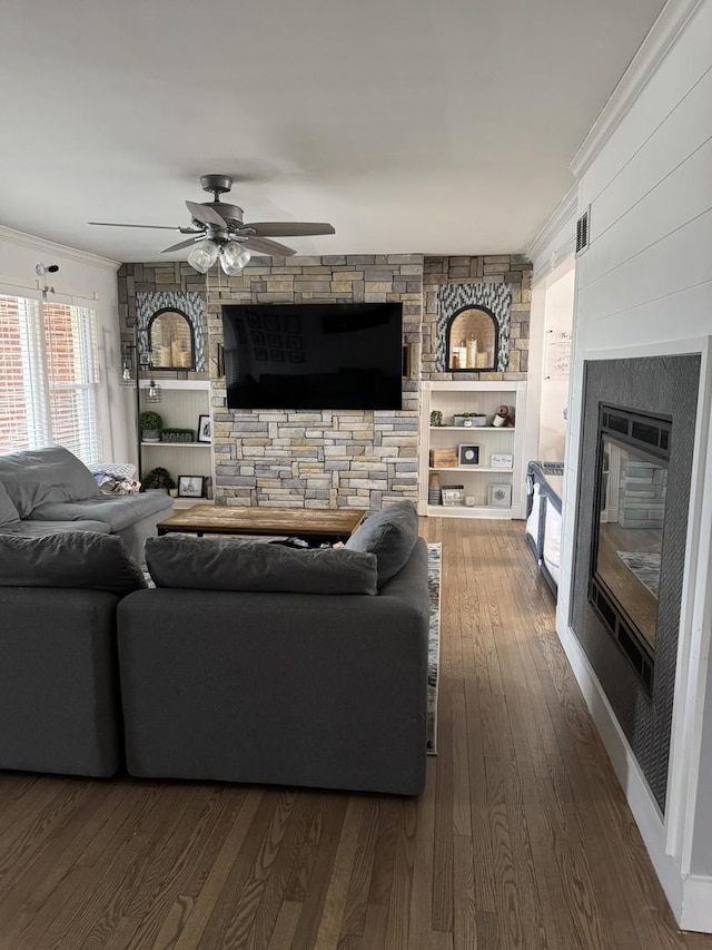 living area featuring a glass covered fireplace, wood finished floors, a ceiling fan, and ornamental molding