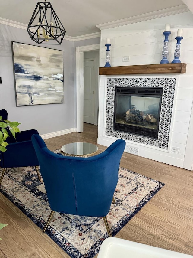 interior space with a fireplace, crown molding, baseboards, and wood finished floors