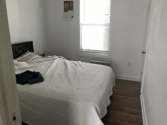 bedroom featuring radiator heating unit, wood finished floors, and baseboards