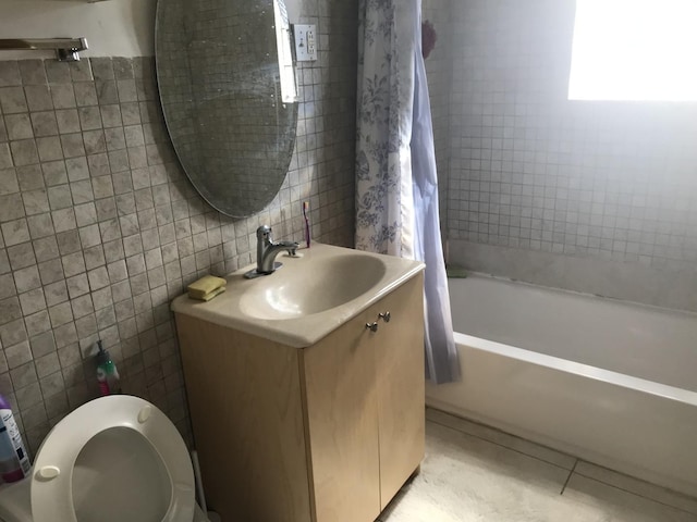 bathroom with toilet, tile patterned flooring, tile walls, shower / bath combination with curtain, and vanity