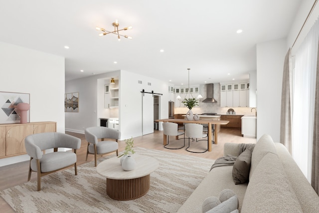 living area with an inviting chandelier, a barn door, recessed lighting, and light wood-style floors