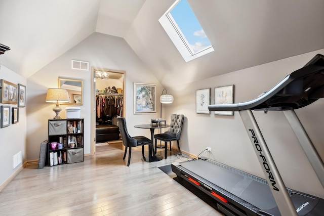 exercise room with visible vents, lofted ceiling with skylight, baseboards, and wood finished floors