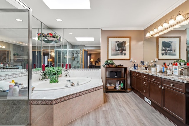 bathroom featuring a shower stall, crown molding, a garden tub, a skylight, and vanity