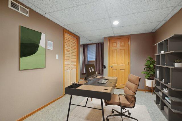 carpeted office space with baseboards, visible vents, and a paneled ceiling