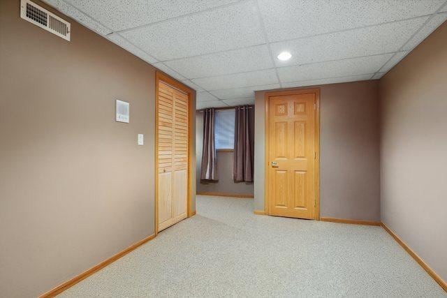 unfurnished room featuring carpet flooring, baseboards, visible vents, and a drop ceiling