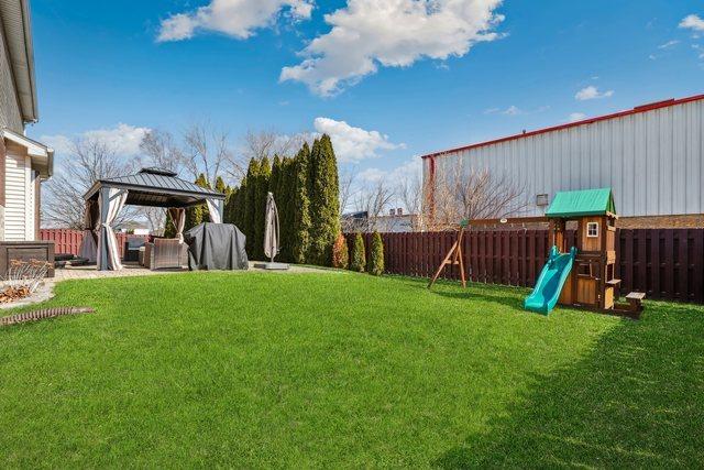 view of yard featuring a gazebo, a fenced backyard, and a playground