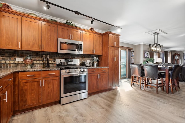 kitchen with decorative backsplash, brown cabinetry, appliances with stainless steel finishes, and ornamental molding