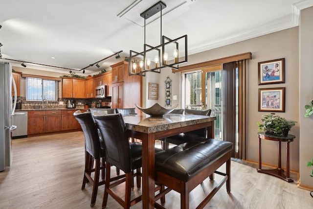 dining space featuring light wood finished floors, a wealth of natural light, and ornamental molding