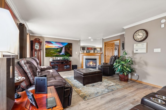 living room with a tiled fireplace, crown molding, wood finished floors, and baseboards