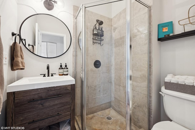 bathroom featuring a shower stall, toilet, and vanity