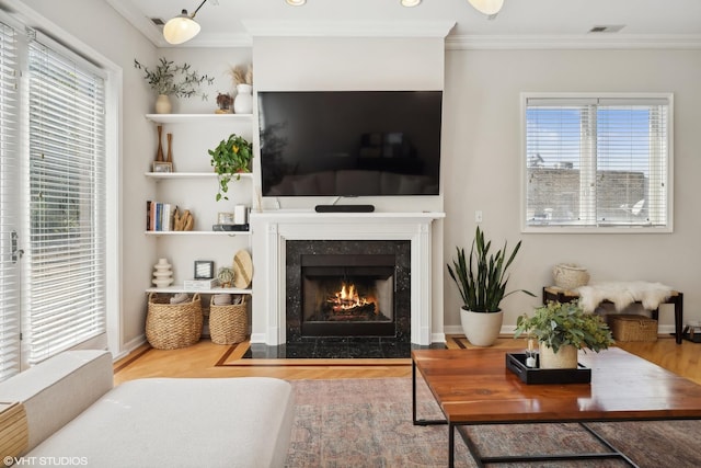 living room with a fireplace, a healthy amount of sunlight, visible vents, and ornamental molding