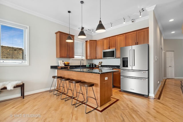 kitchen featuring stainless steel appliances, brown cabinets, a breakfast bar, and ornamental molding