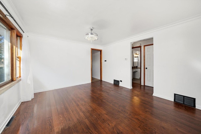 unfurnished room featuring baseboards, wood finished floors, visible vents, and ornamental molding