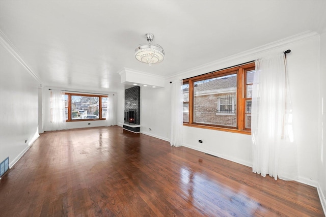 unfurnished living room with baseboards, a brick fireplace, wood finished floors, and crown molding