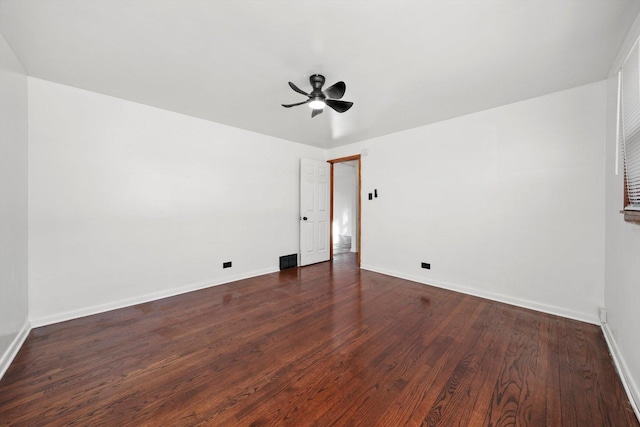 spare room featuring dark wood-type flooring, a ceiling fan, baseboards, and visible vents