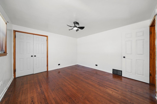 unfurnished bedroom with baseboards, visible vents, dark wood-style flooring, ceiling fan, and a closet