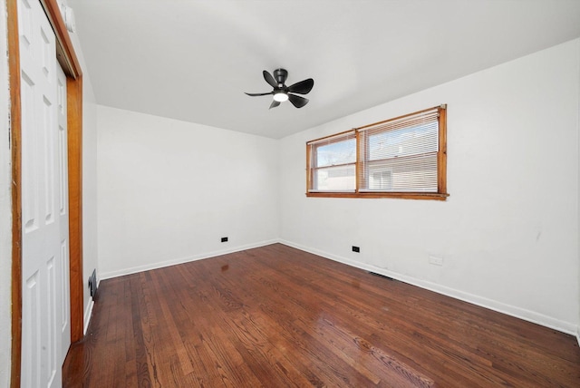 spare room featuring ceiling fan, baseboards, and dark wood finished floors