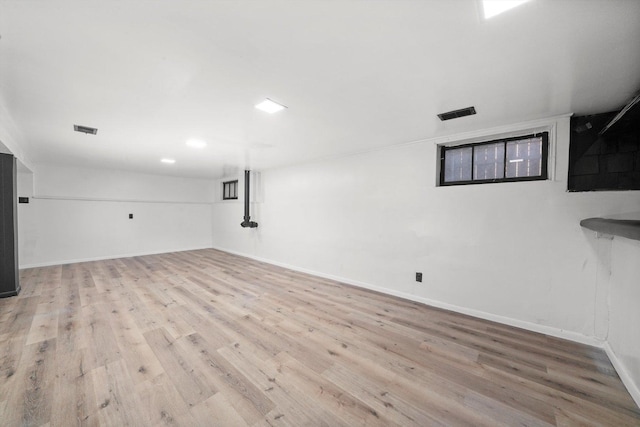 finished below grade area with visible vents, baseboards, and wood finished floors