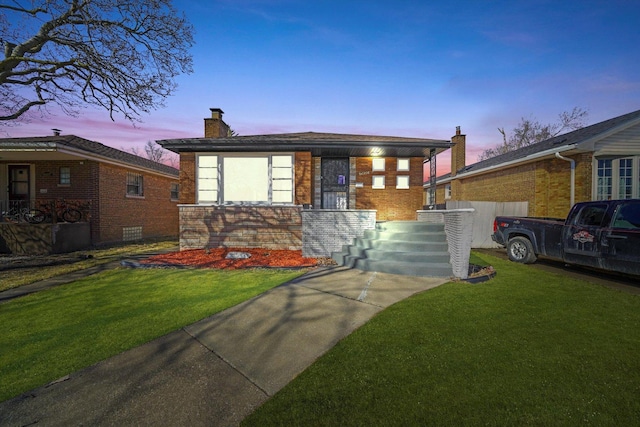 view of front of property with brick siding, a lawn, and a chimney