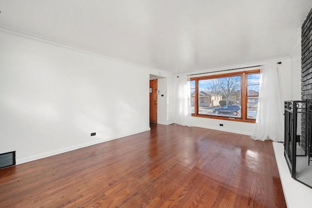 unfurnished living room featuring baseboards, wood finished floors, visible vents, and ornamental molding