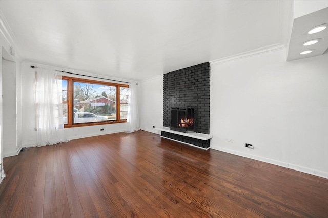 unfurnished living room with baseboards, a brick fireplace, wood finished floors, and crown molding