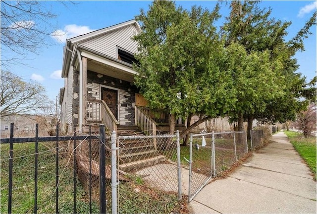 view of front of property featuring a fenced front yard, stone siding, and a gate