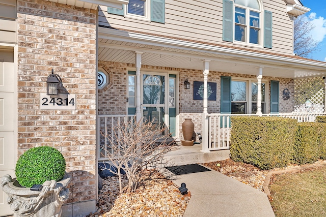 entrance to property featuring brick siding and a porch