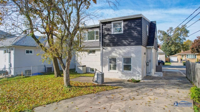 rear view of property with brick siding, an outdoor structure, central AC, and fence