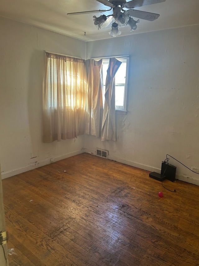 empty room with visible vents, baseboards, ceiling fan, and wood-type flooring