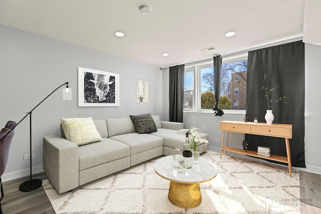 living room with recessed lighting, visible vents, baseboards, and wood finished floors