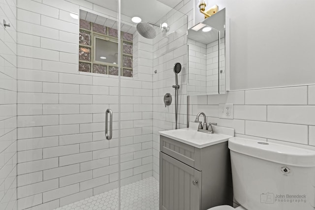 full bath featuring vanity, a shower stall, toilet, and tile walls