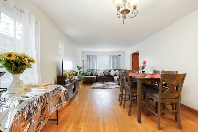 dining room with an inviting chandelier, light wood-style flooring, and baseboards