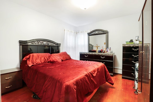 bedroom with baseboard heating and wood finished floors