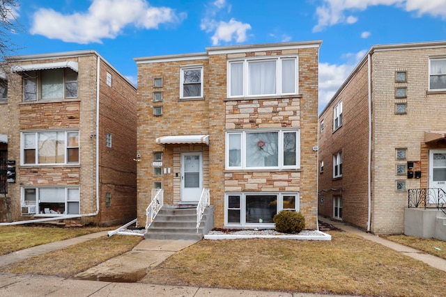 multi unit property featuring a front yard, cooling unit, brick siding, and stone siding