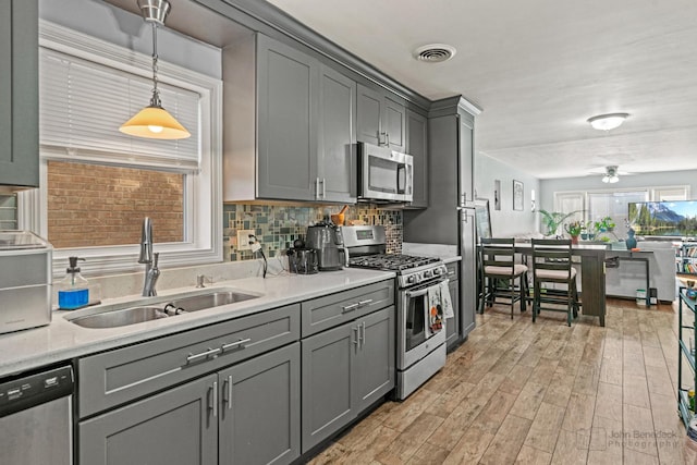 kitchen featuring visible vents, gray cabinets, a sink, tasteful backsplash, and stainless steel appliances